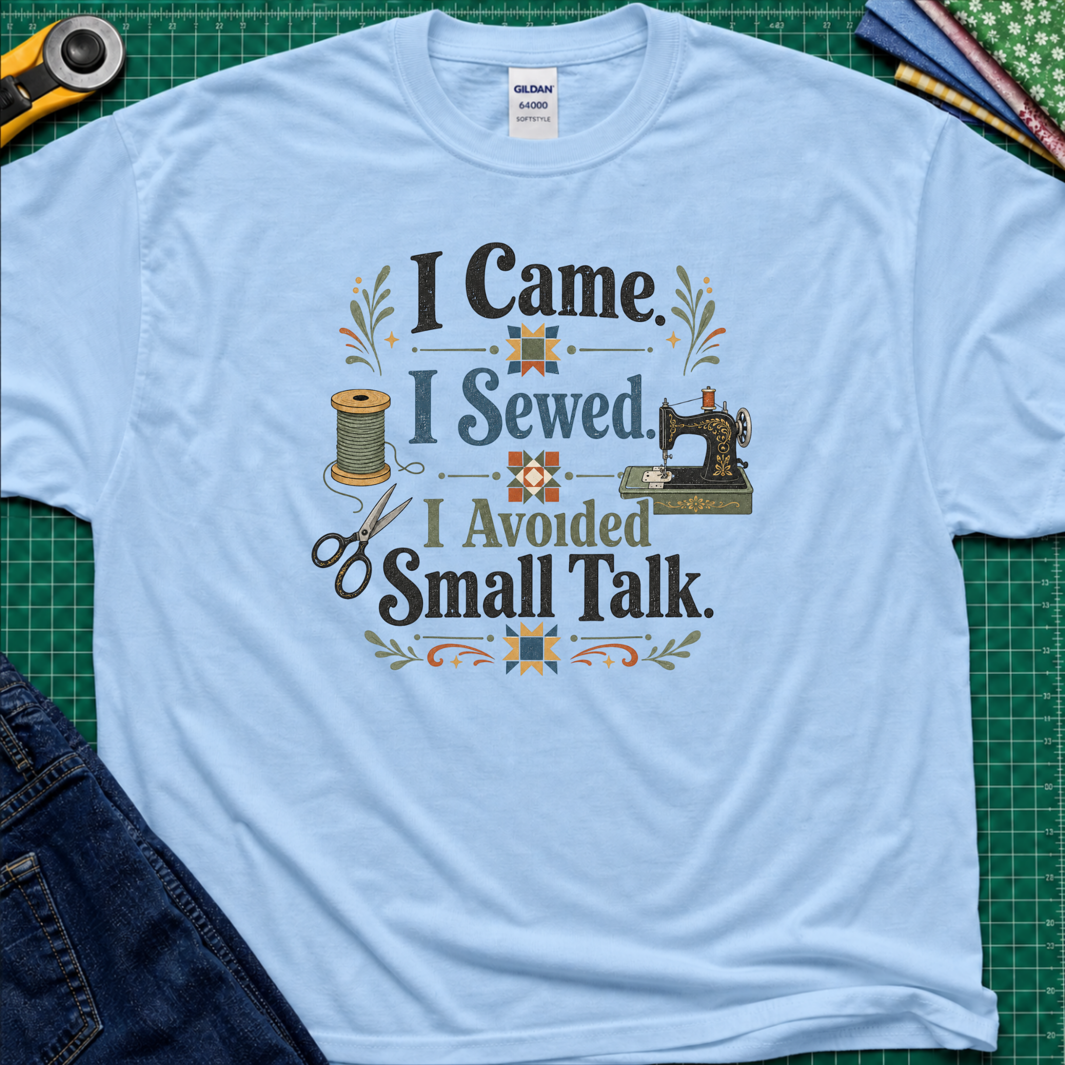 A light blue Gildan t-shirt with a retro-style sewing-themed graphic that reads 'I Came I Sewed. I Avoided Small Talk.