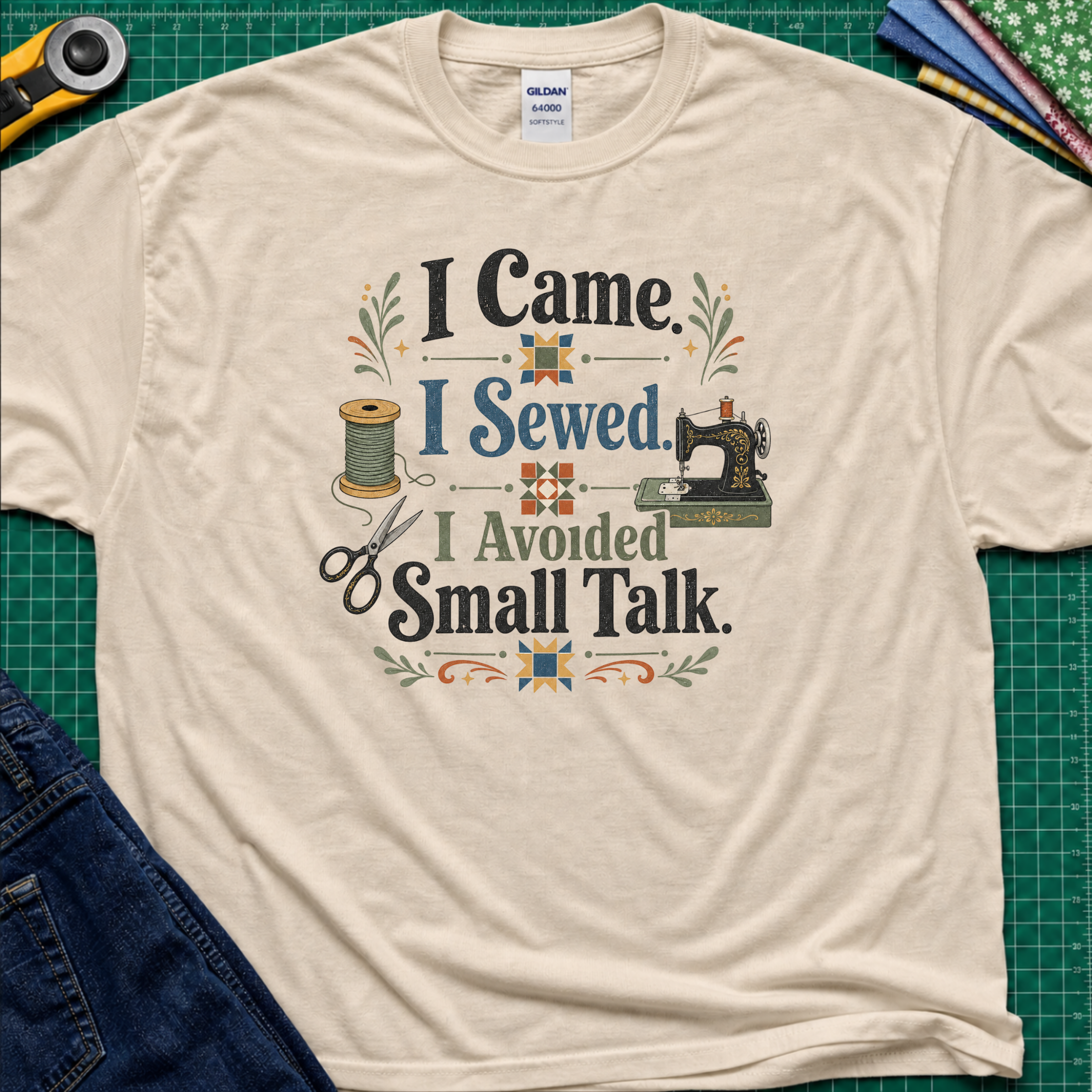 A dark cream Gildan t-shirt with a retro-style sewing-themed graphic that reads 'I Came I Sewed. I Avoided Small Talk.