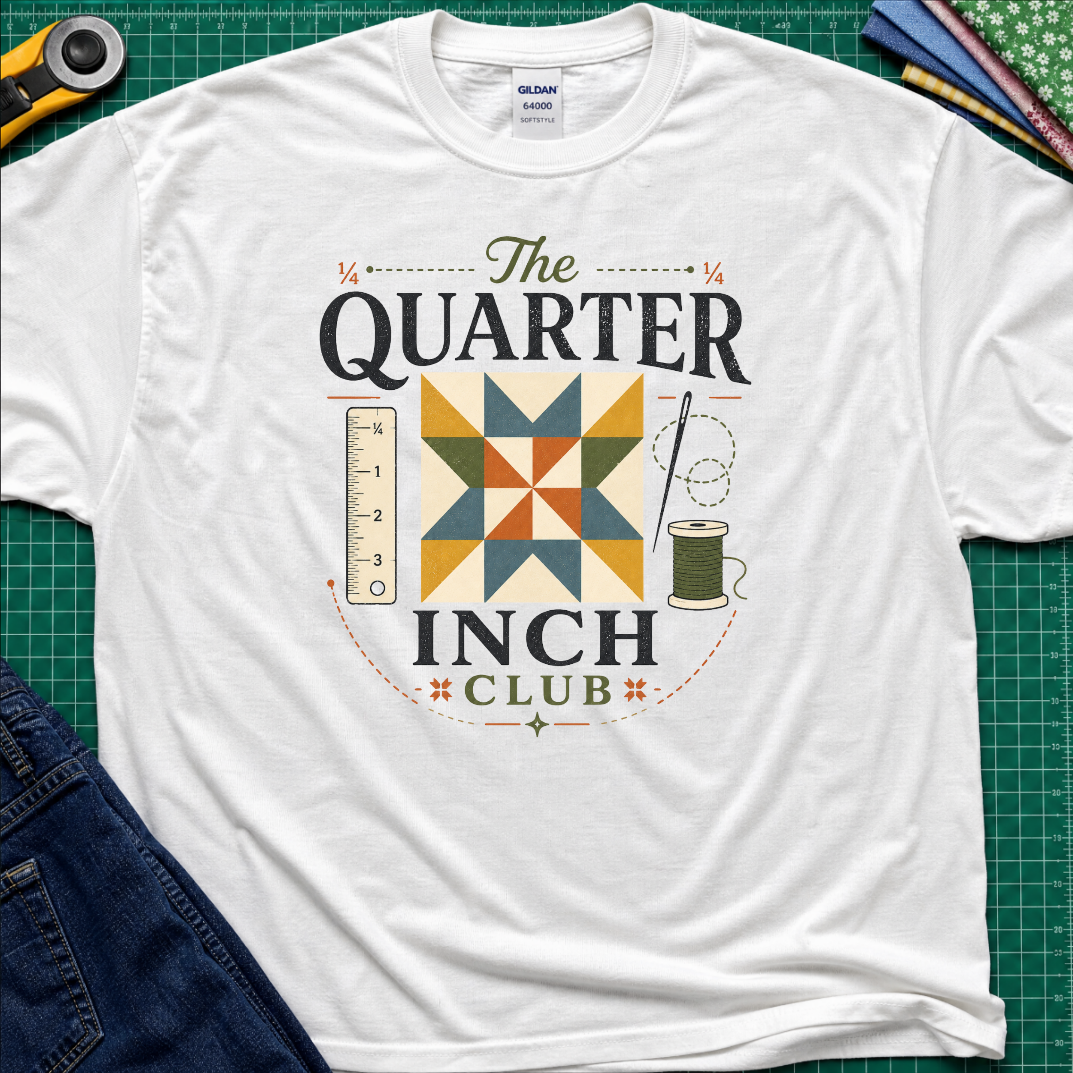 A white Gildan t-shirt with a retro-style quilted graphic that reads 'The QUARTER INCH CLUB'. The graphic features a geometric quilt pattern in yellow, orange, and blue, alongside a sewing ruler, spool, and needle.
